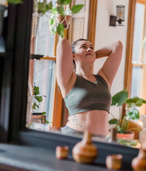Woman in a calm yoga pose in a dark room with mint green light accents.